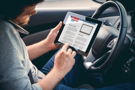 man using tablet and phone while driving